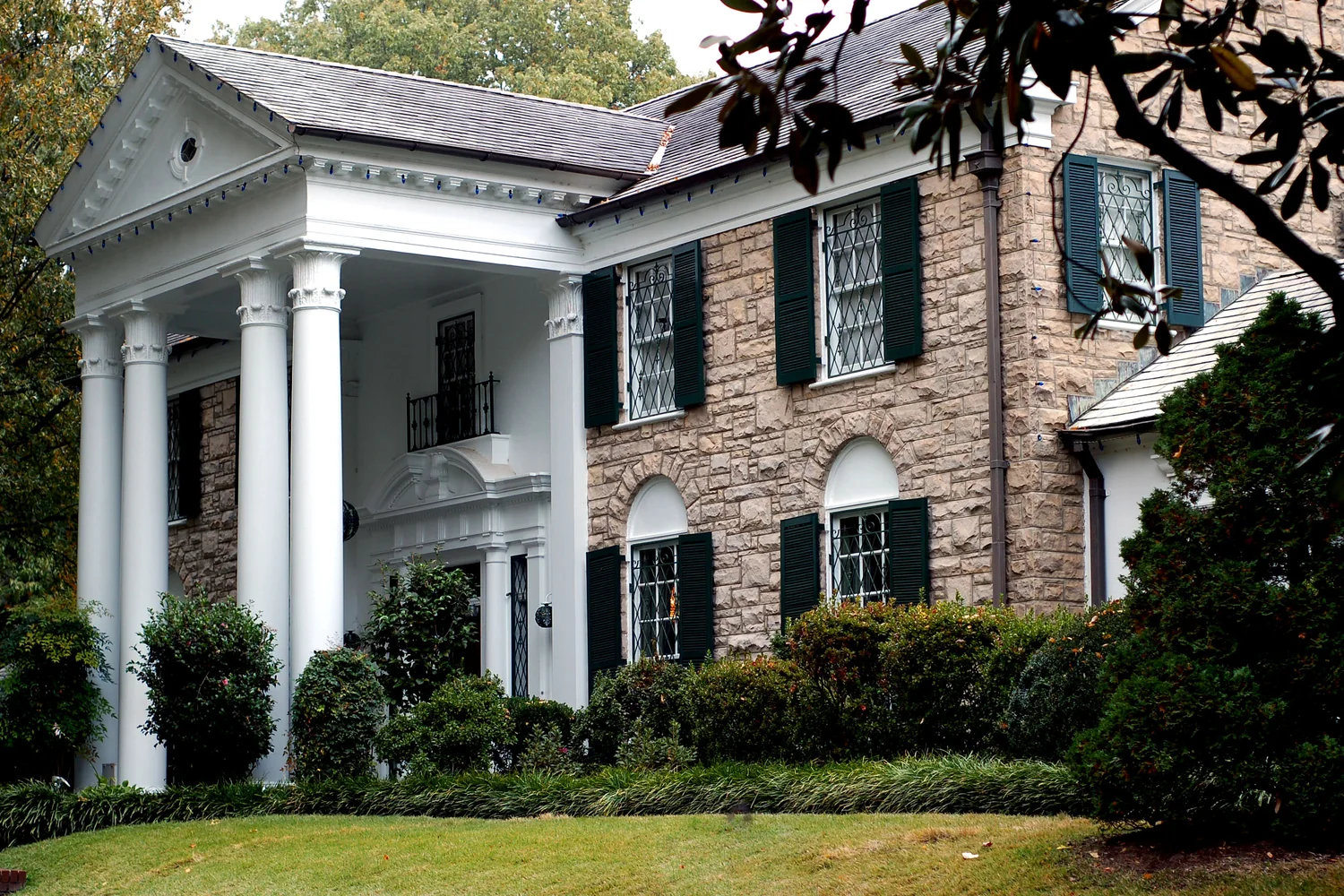 Graceland’s white-columned stone facade framed by trees and green lawn.