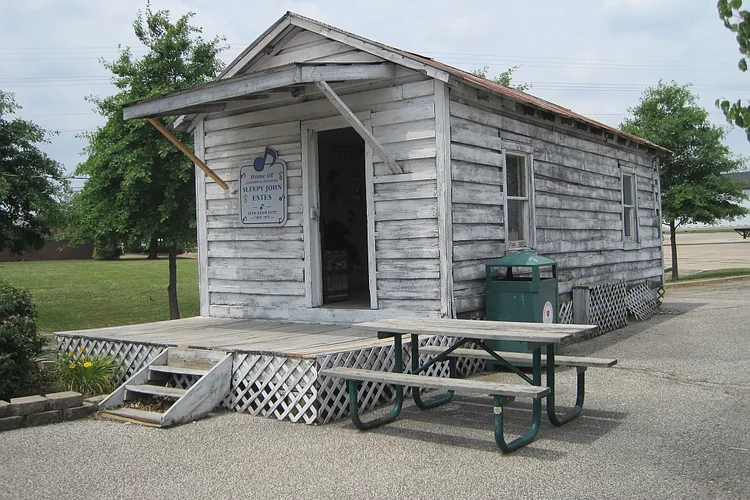 Weathered wooden home of Sleepy John Estes with a small front porch and picnic table at the West Tennessee Delta Heritage Center.